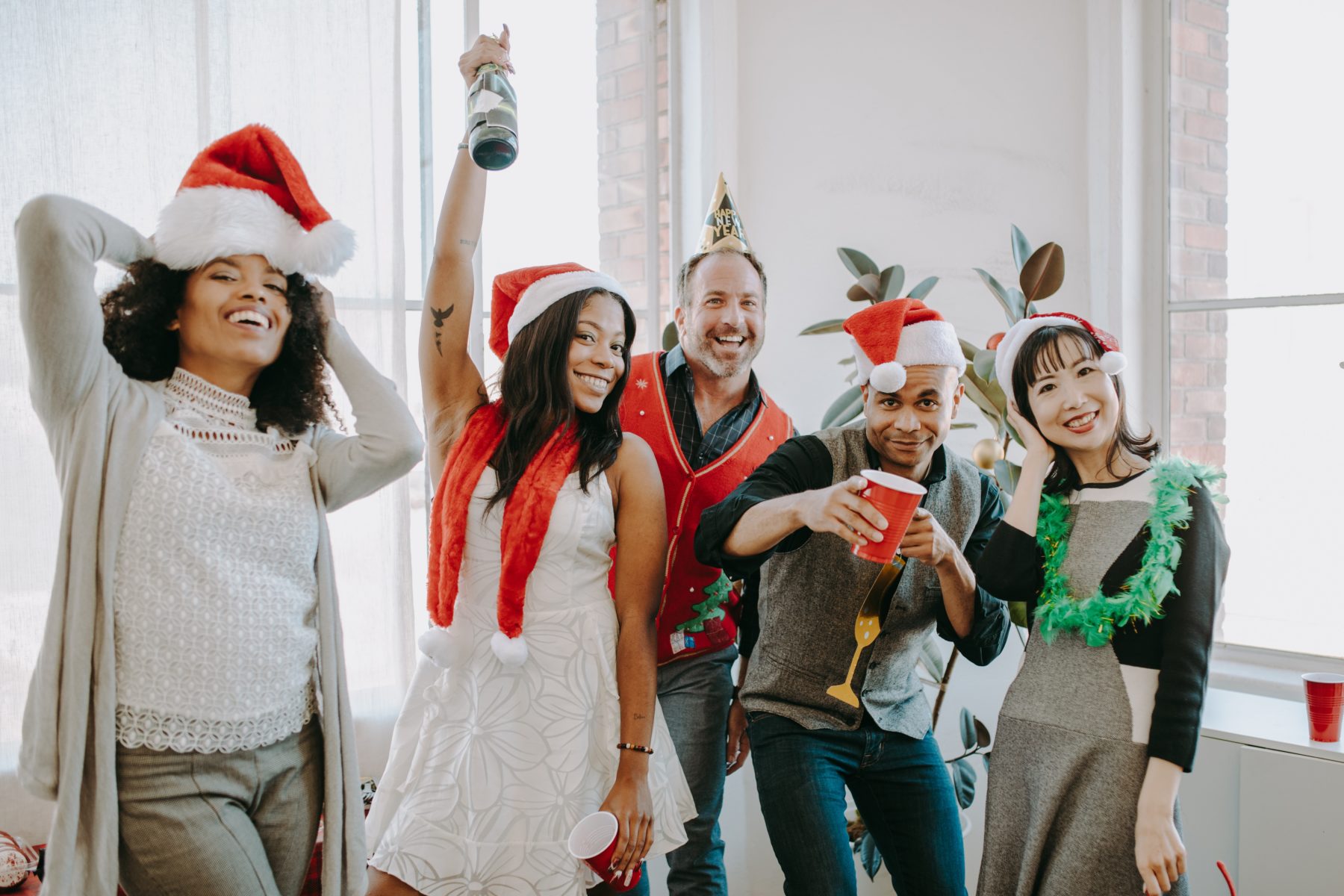 A group of men and women in santa and other festive hats.