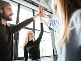 Happy colleagues in office give high five to each other