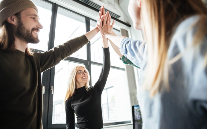 Happy colleagues in office give high five to each other