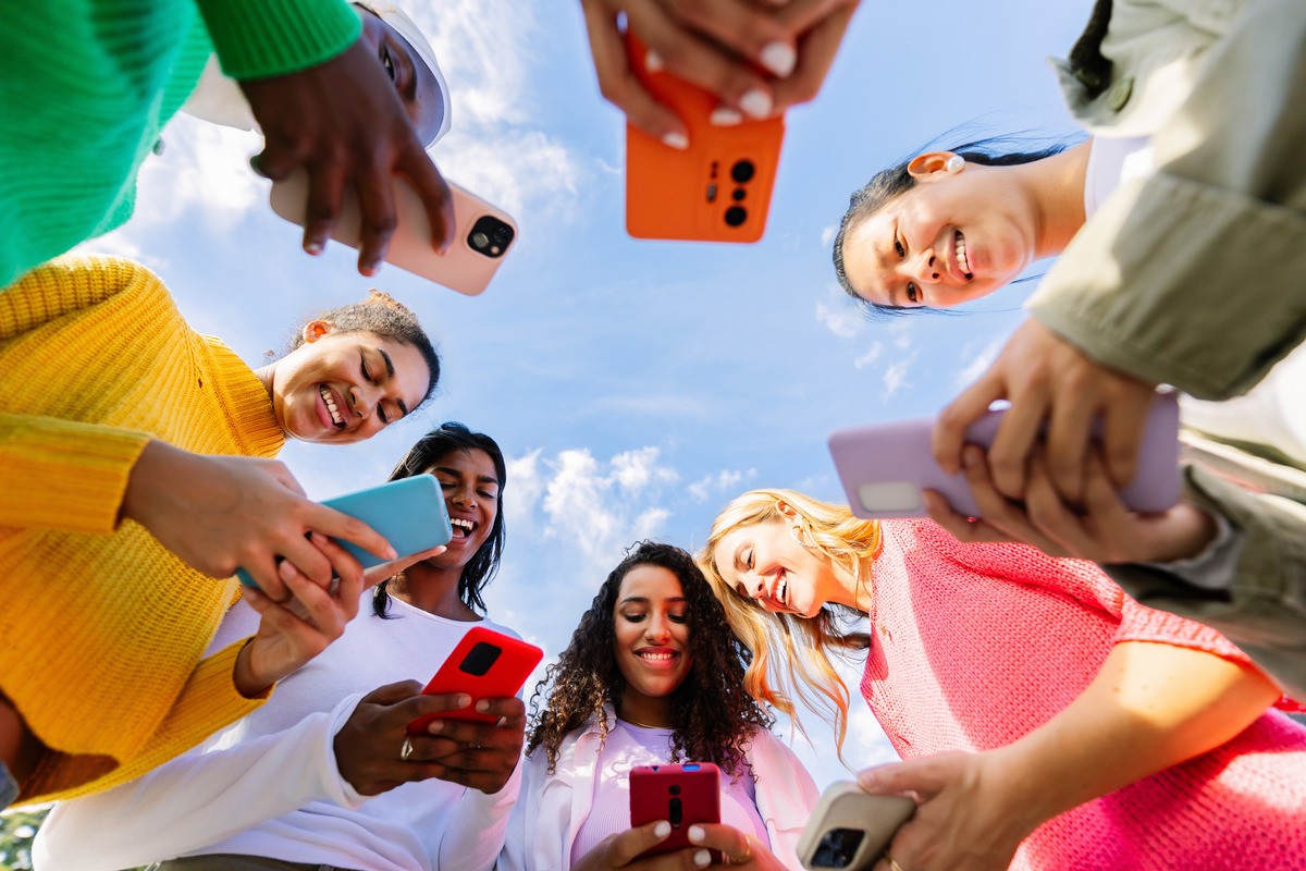 EvotoLow angle view of young group of multicultural women using mobile phones.