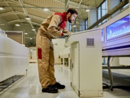 Production line worker operating automated machine at woodworking industrial facility