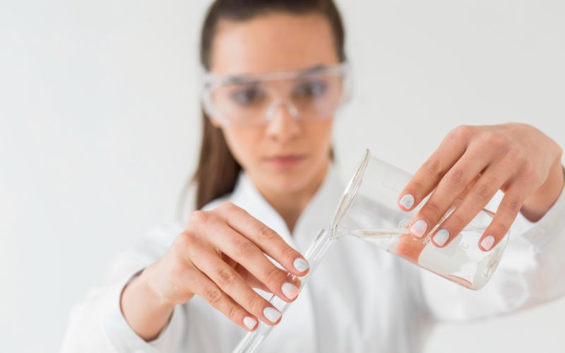 Front view of female scientist with safety glasses and potions