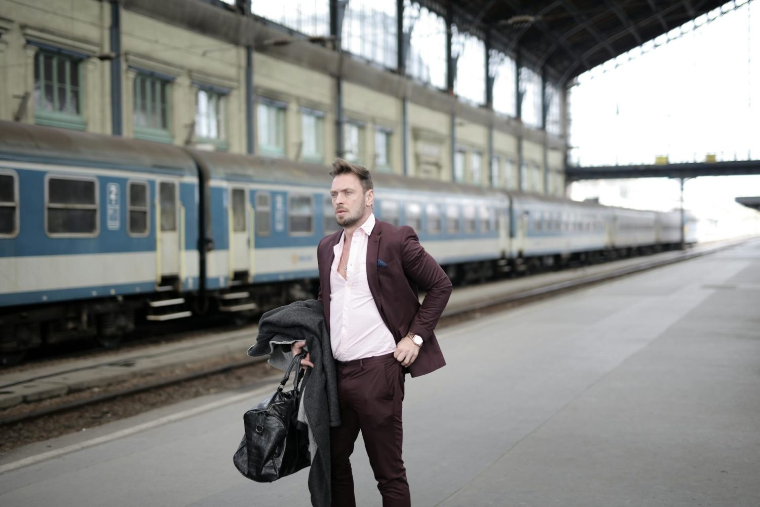 Businessman standing on platform and waiting for train on railway station