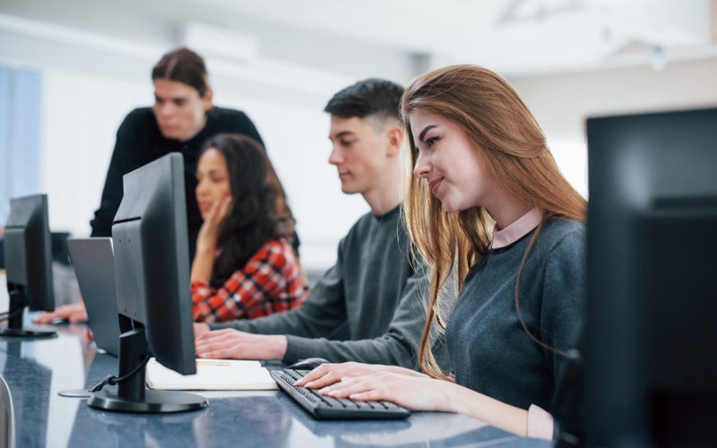 Computer screens. Group of young people in casual clothes working in the modern office