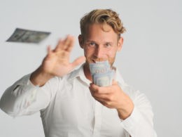 excited blond bearded businessman happily throwing money into camera