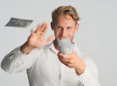 excited blond bearded businessman happily throwing money into camera