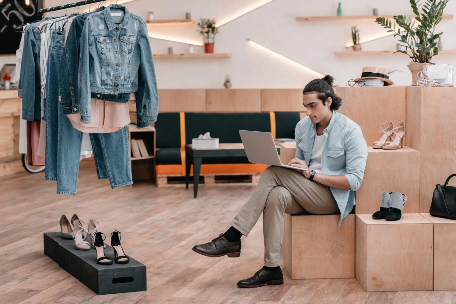 Concentrated young man using laptop while sitting and working in boutique