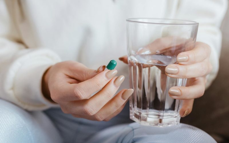 Woman Holding Pill and Glass of Water