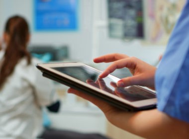 Close up of nurse holding and typing on tablet