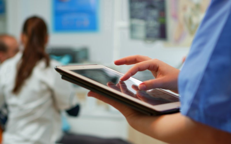 Close up of nurse holding and typing on tablet