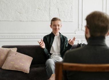 Man in Black Suit Jacket Sitting on Brown Wooden Chair
