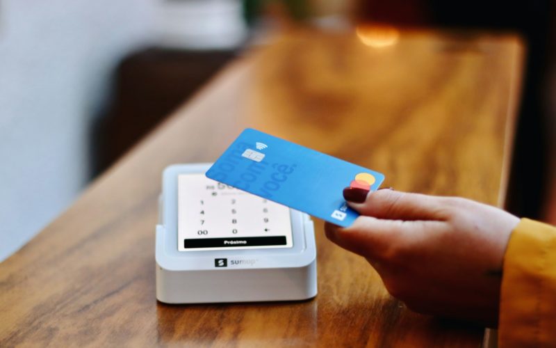 a person holding a credit card in front of a machine