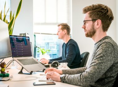 man sitting on chair wearing gray crew-neck long-sleeved shirt using Apple Magic Keyboard