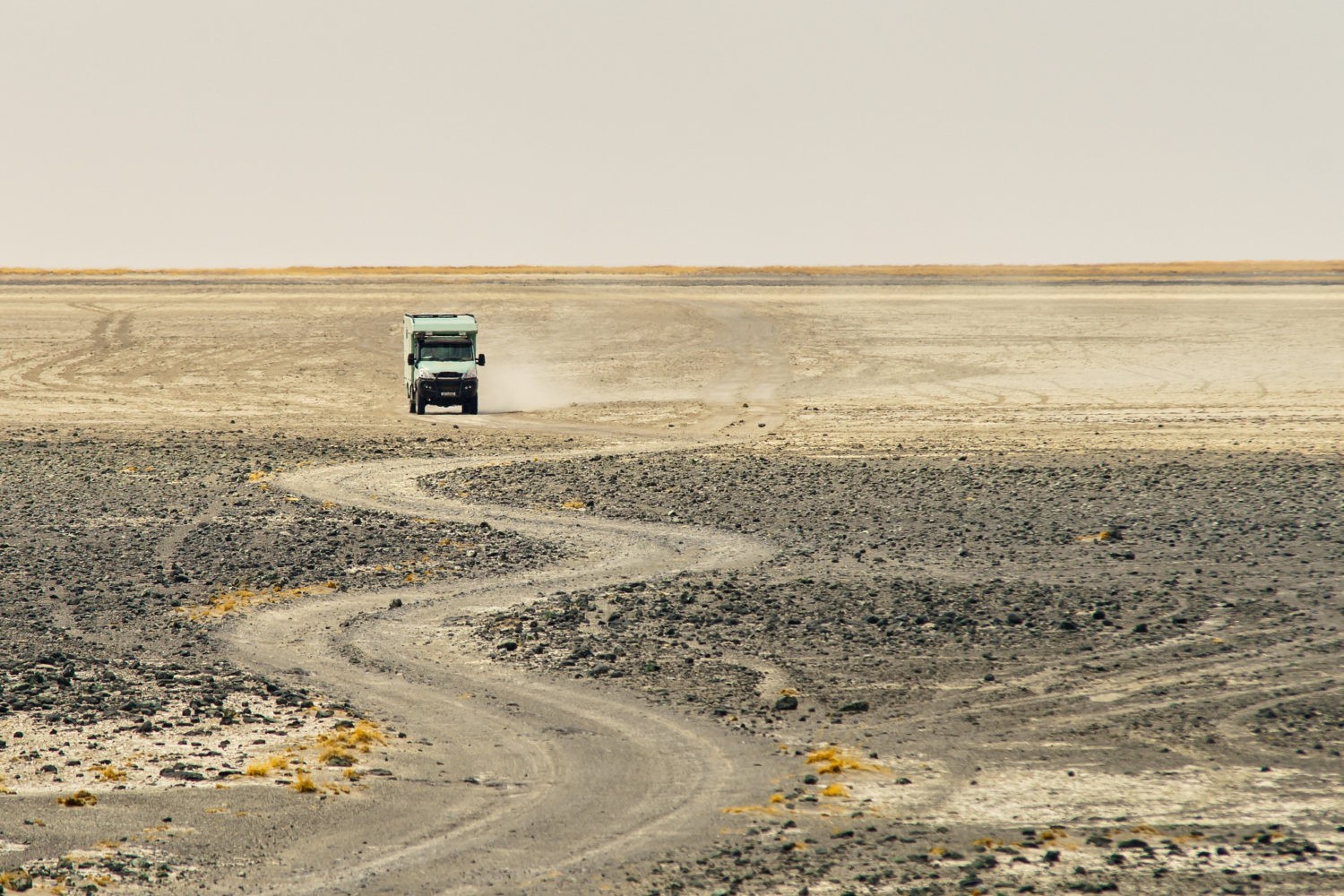 Truck riding through a curvy rocky road making dust