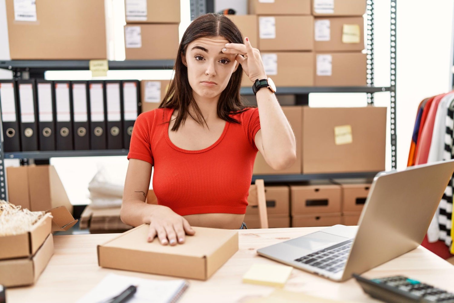 Young hispanic woman preparing order working at storehouse worried and stressed about a problem with hand on forehead nervous and anxious for crisis