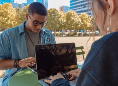 man and woman sitting while using MacBook Pro