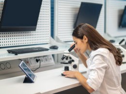 Woman sitting at table looking through microscope