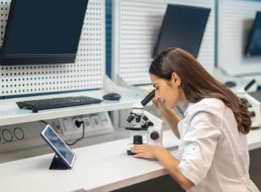 Woman sitting at table looking through microscope