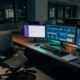 Office desk with active workflow dashboards on screens and no person present, representing autonomous AI operations