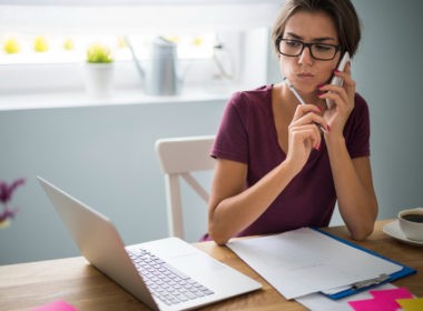 A remote worker sitting at a desk with a laptop open, looking distracted and disengaged