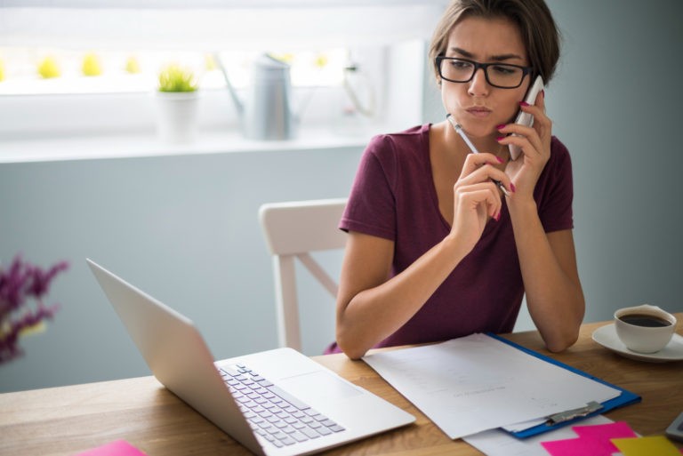 A remote worker sitting at a desk with a laptop open, looking distracted and disengaged