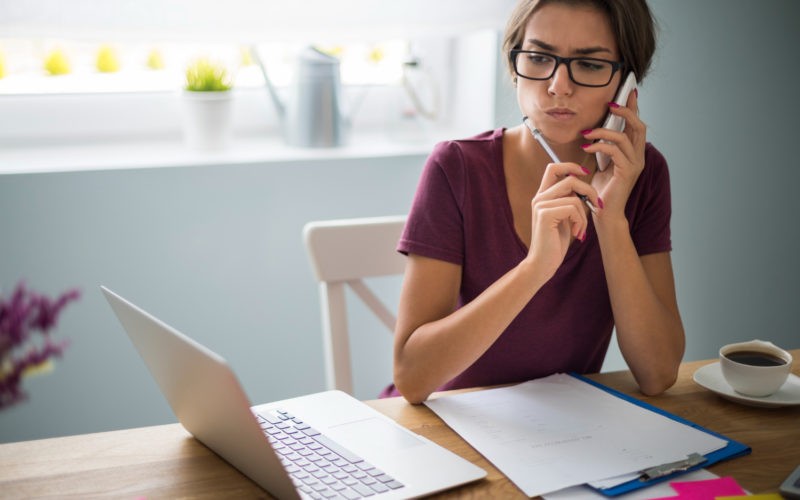 A remote worker sitting at a desk with a laptop open, looking distracted and disengaged