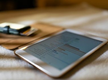 Close-up of a tablet displaying financial graphs on a soft white surface, ideal for business concepts.