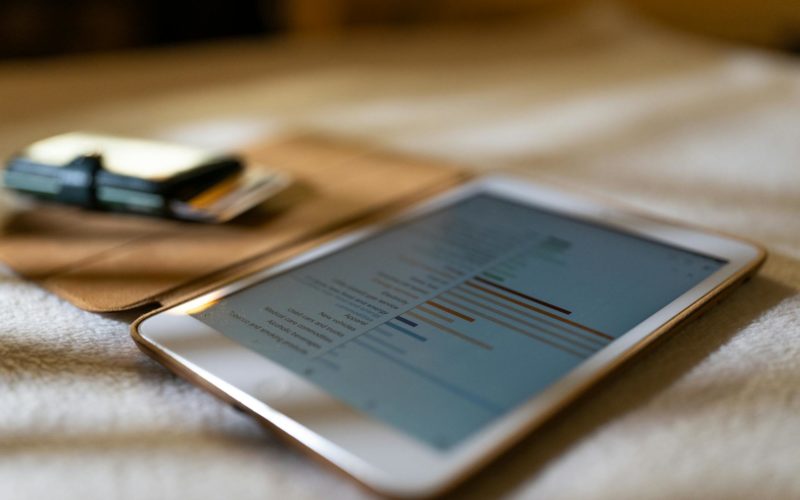 Close-up of a tablet displaying financial graphs on a soft white surface, ideal for business concepts.